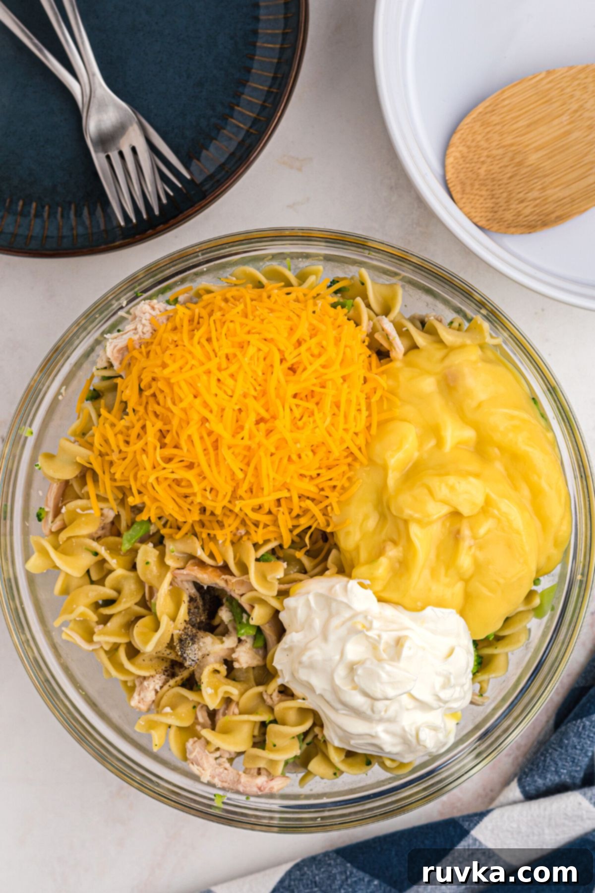 Crispy Air Fryer Chicken Casserole 5 Cheese, sour cream, seasonings, chicken, noodles, and broccoli mixed together in a clear glass bowl, showcasing the creamy texture.
