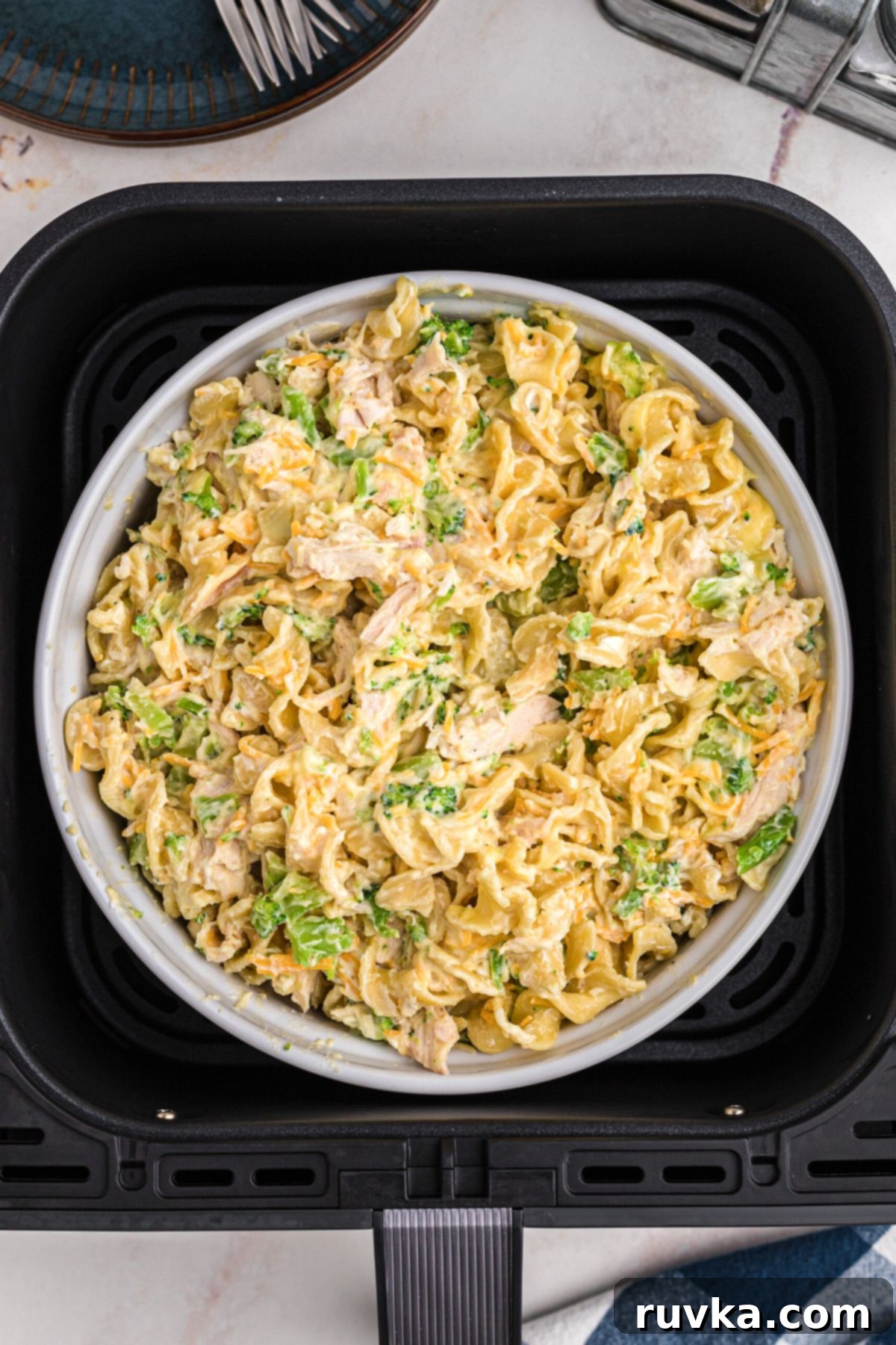 Crispy Air Fryer Chicken Casserole 7 Chicken casserole in a white baking dish inside the basket of an air fryer, ready for cooking.