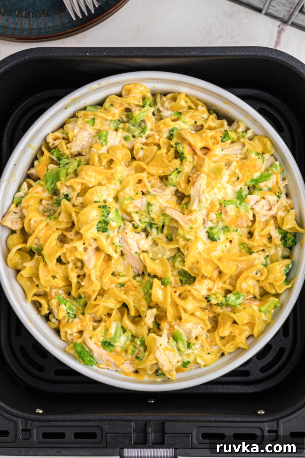 Crispy Air Fryer Chicken Casserole 8 Golden cheesy pasta and chicken mixed in a casserole dish, fresh out of the air fryer basket and ready to be served.