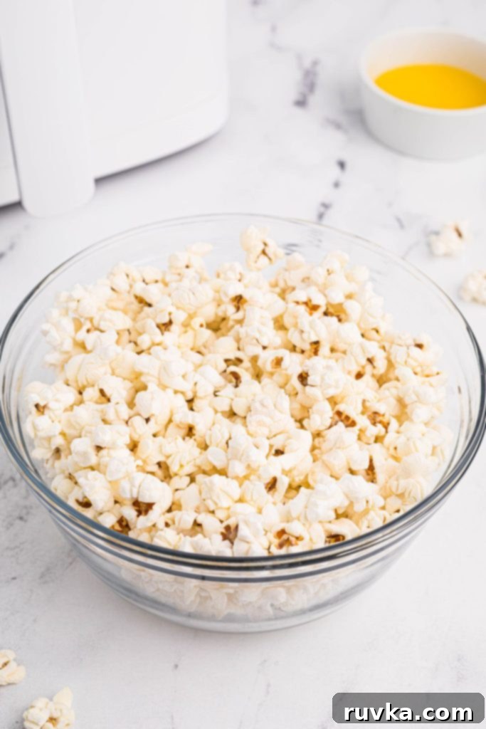 Air-Popped Perfection 2 White fluffy popcorn in a clear glass bowl with melted butter in a small bowl