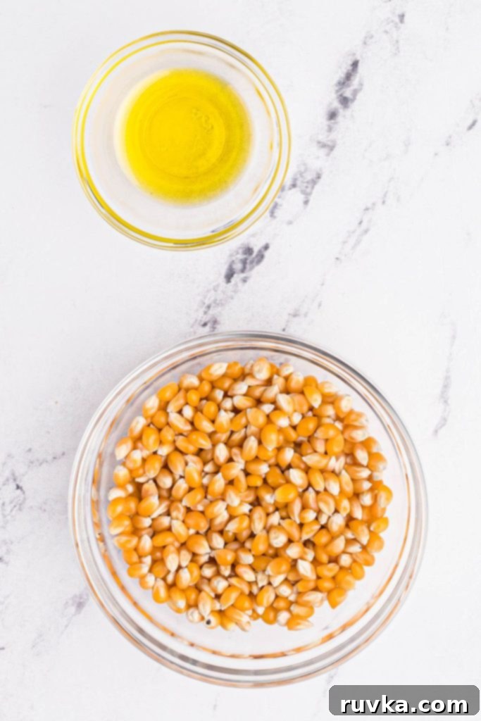 Air-Popped Perfection 4 Popcorn kernels and melted butter in glass bowls on a marble table.