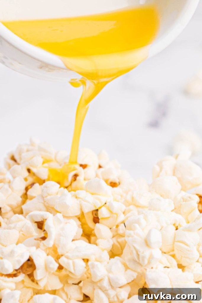 Air-Popped Perfection 7 Melted butter being poured over popped popcorn in a glass bowl