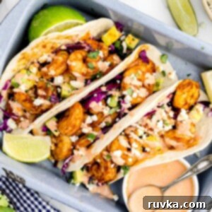 Crispy Air Fryer Shrimp Tacos 11 Shrimp tacos stuffed and stacked in a gray baking pan, garnished with lime.