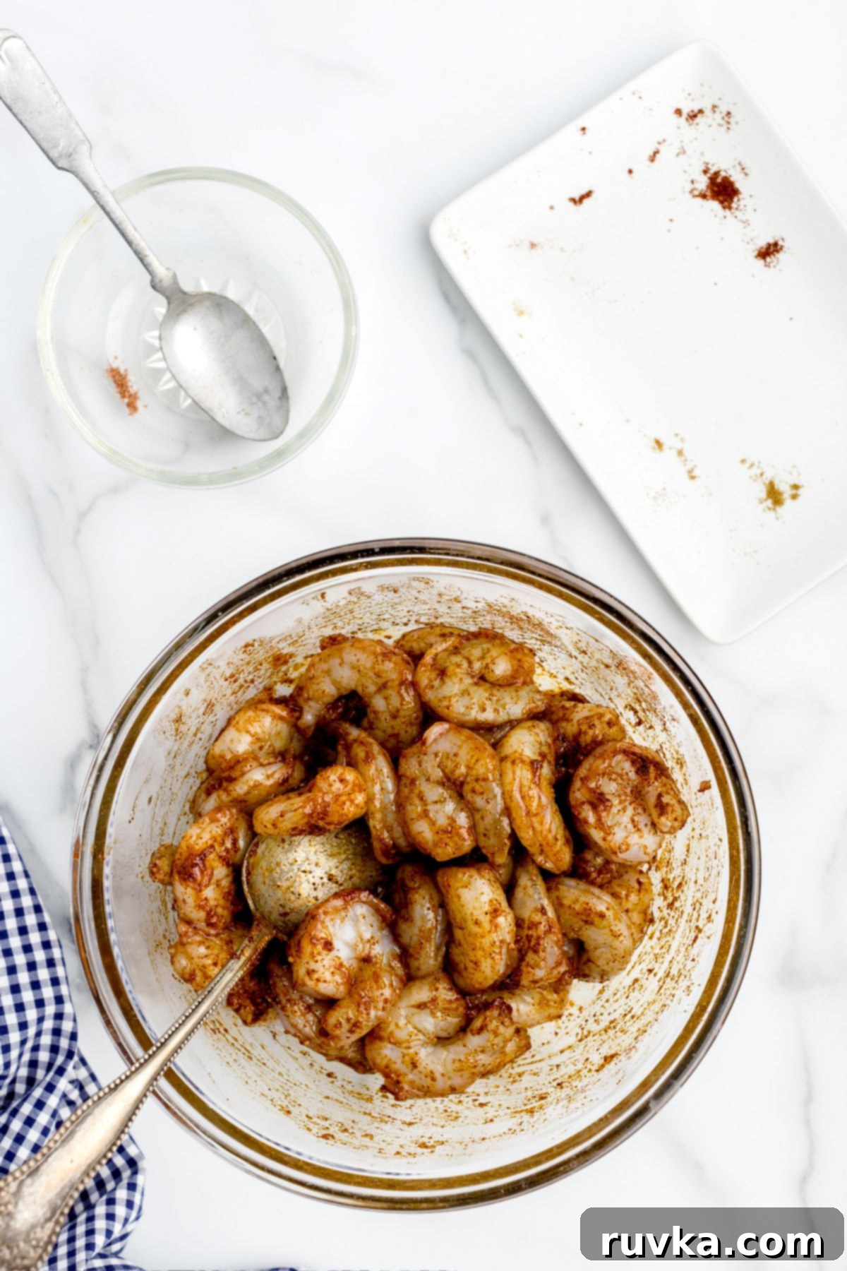 Crispy Air Fryer Shrimp Tacos 5 Uncooked shrimp in a clear glass bowl tossed with a vibrant seasoning blend.