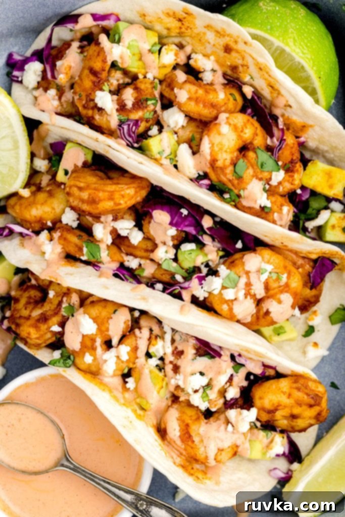 Crispy Air Fryer Shrimp Tacos 9 Shrimp tacos neatly arranged in a pan with the spicy crema and fresh lime wedges.