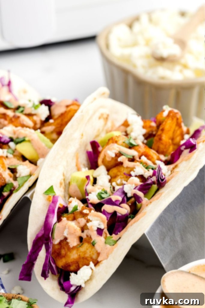 Crispy Air Fryer Shrimp Tacos 10 Perfectly assembled shrimp tacos, stuffed and neatly stacked in a taco holder, ready for serving.