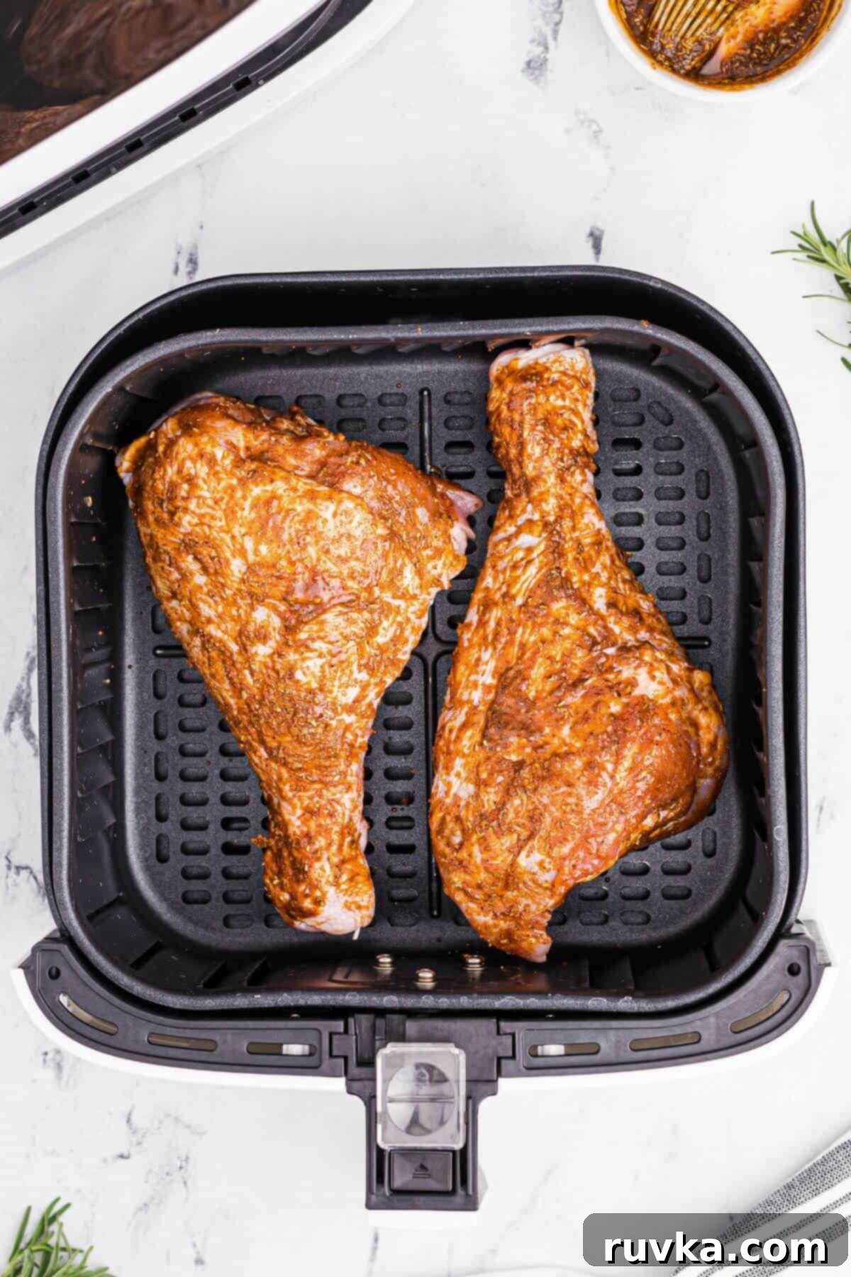 Crispy Air Fryer Turkey Legs 6 Seasoned turkey legs in the air fryer basket before being cooked.