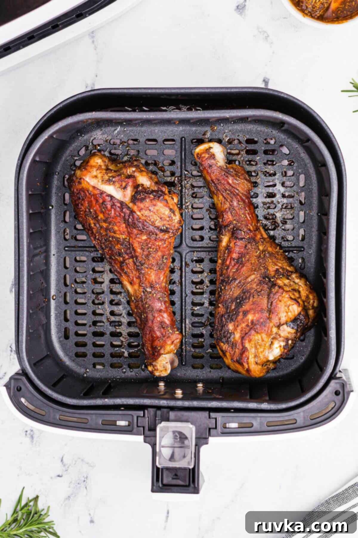 Crispy Air Fryer Turkey Legs 7 Golden brown seasoned turkey legs in the air fryer basket after being cooked.