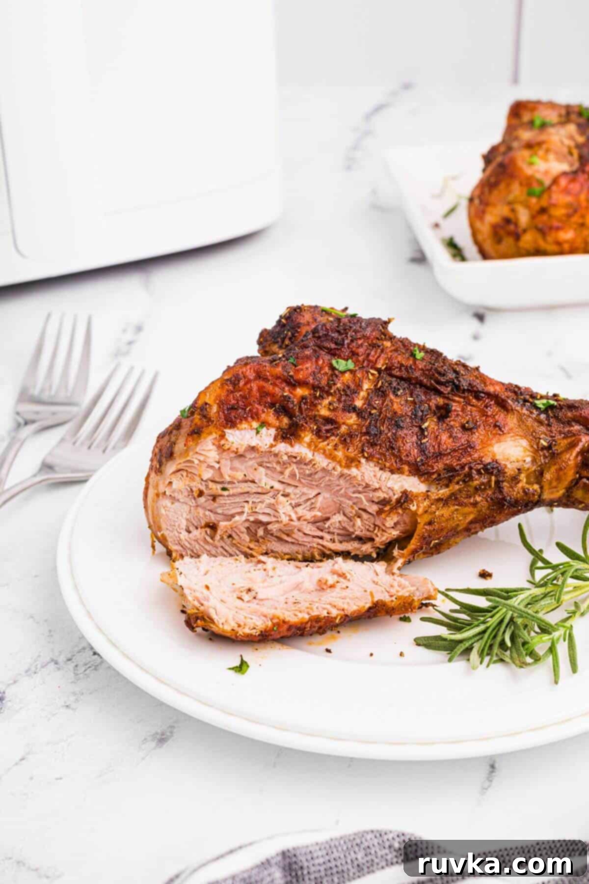 Crispy Air Fryer Turkey Legs 8 Golden brown turkey leg on a white plate with a small slice cut