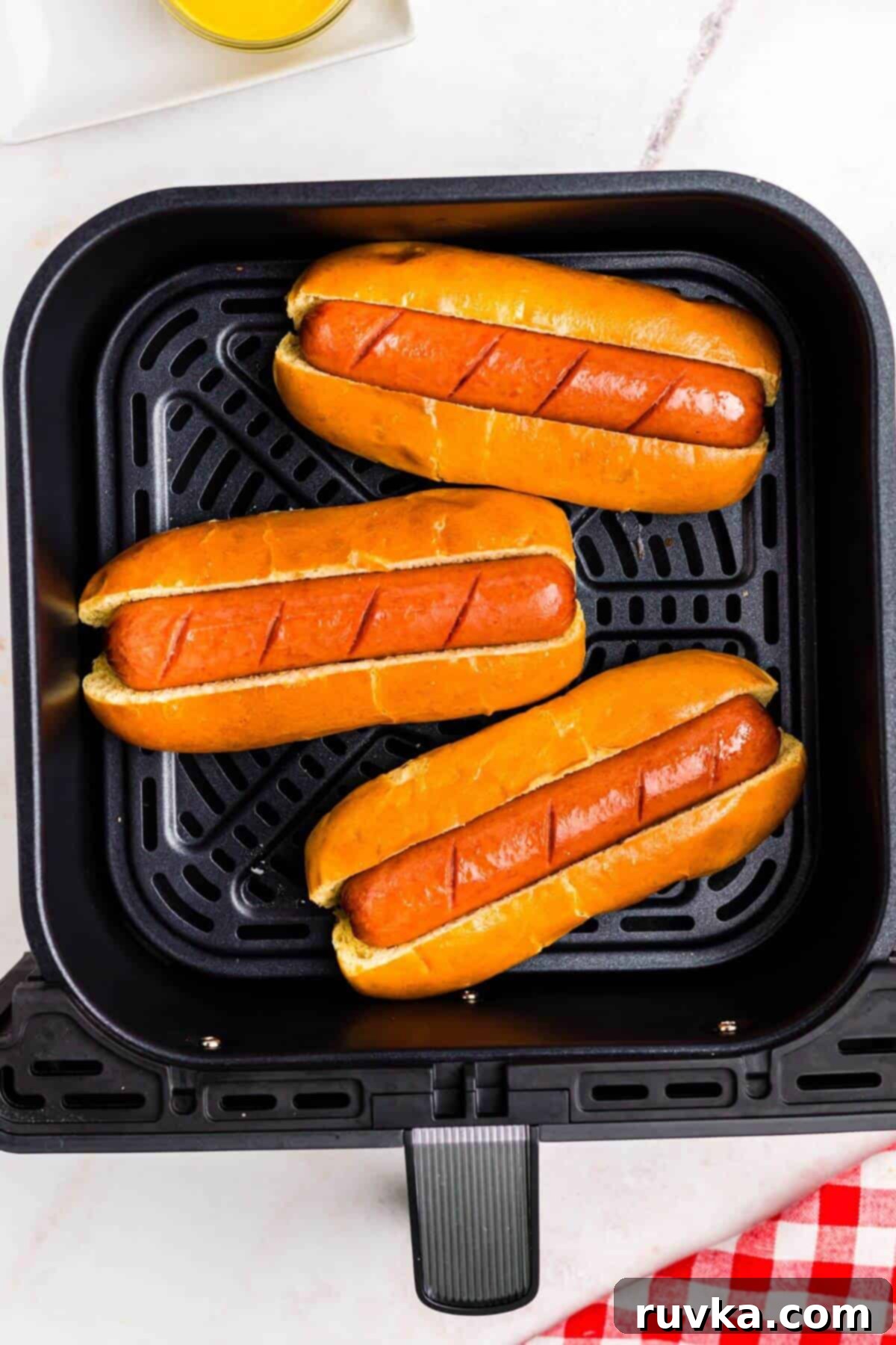 Air Fryer Hot Dog Hack 2 Golden juicy hot dogs in buns in the air fryer basket.