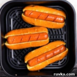 Air Fryer Hot Dog Hack 8 Juicy brown hot dogs in buns in the air fryer basket.