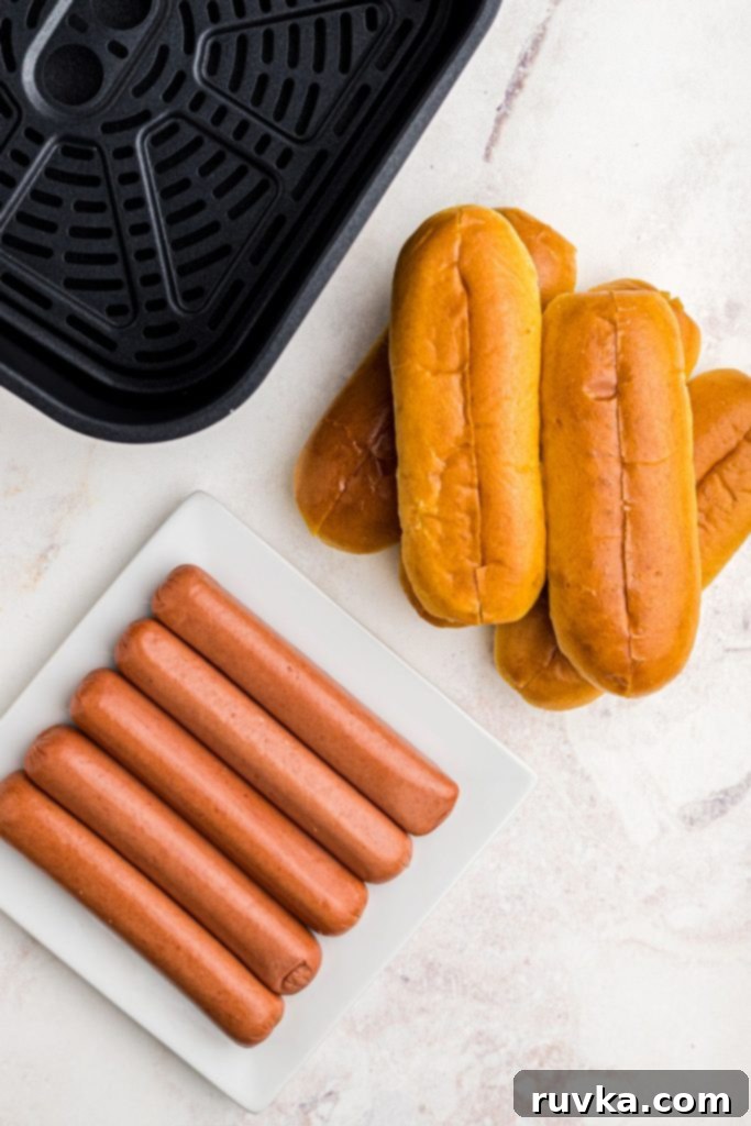 Air Fryer Hot Dog Hack 3 Ingredients like buns and uncooked hot dogs in front of an air fryer basket.