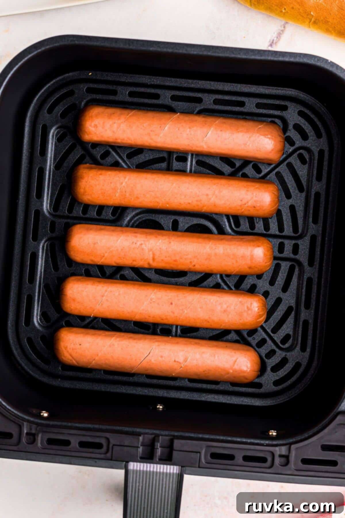 Air Fryer Hot Dog Hack 5 Uncooked hot dogs in the air fryer basket.