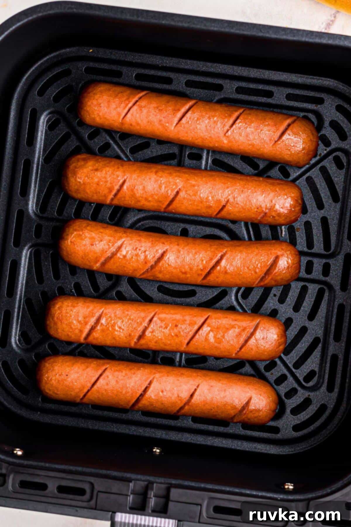 Air Fryer Hot Dog Hack 6 Juicy brown franks in the air fryer basket after being cooked.