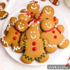 Easy Air Fryer Christmas Cookies 3 Golden gingerbread cookies on a white plate frosted with red, white, and green frosting, ready for holiday celebrations.