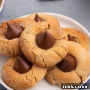 Easy Air Fryer Christmas Cookies 5 Golden peanut butter cookies adorned with chocolate kisses, arranged on a white plate for a delicious holiday treat.