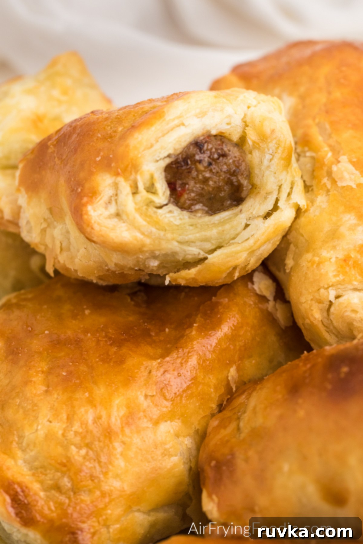 Perfect Air Fryer Sausage Rolls 8 Close up shot of sausage rolls made in the air fryer and served on a platter. Detail of the flaky pastry and savory filling.