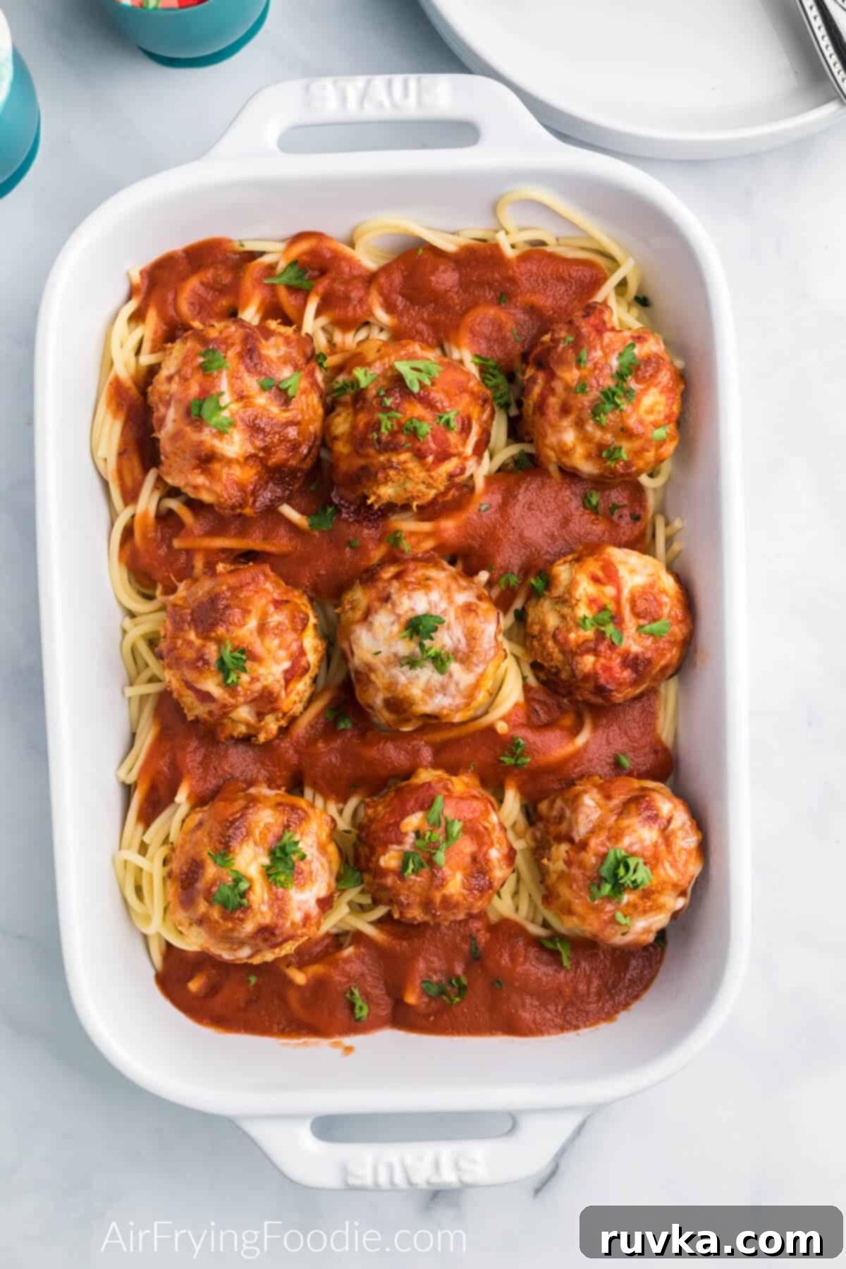 Crispy Air Fryer Chicken Parmesan Meatballs 2 Air fryer chicken meatballs topped with marinara sauce and cheese and served over a dish of spaghetti noodles.