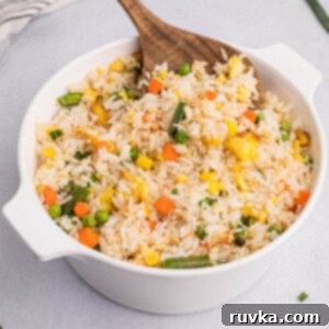 Quick Air Fryer Fried Rice 14 Close-up picture of air fryer fried rice in a large serving bowl with a wooden spoonful of the fried rice.