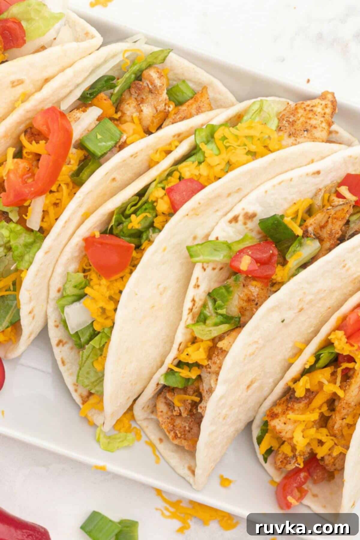 Crispy Air Fryer Chicken Street Tacos 6 Seasoned cooked chicken pieces in a flour tortilla topped with shredded cheese and chopped tomatoes.