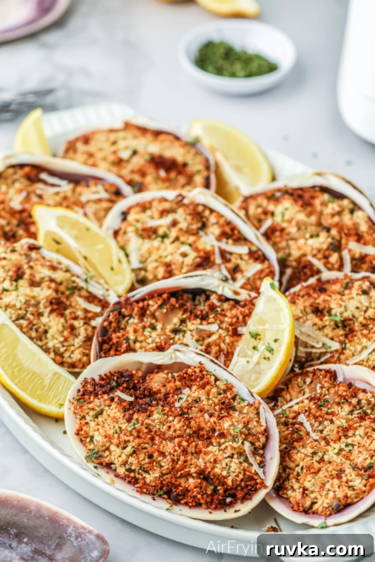 Crispy Air Fryer Stuffed Clams 9 A beautifully presented serving of air fried stuffed clams on a pristine white plate, accompanied by vibrant lemon wedges, suggesting a fresh and ready-to-eat appetizer perfect for any occasion.