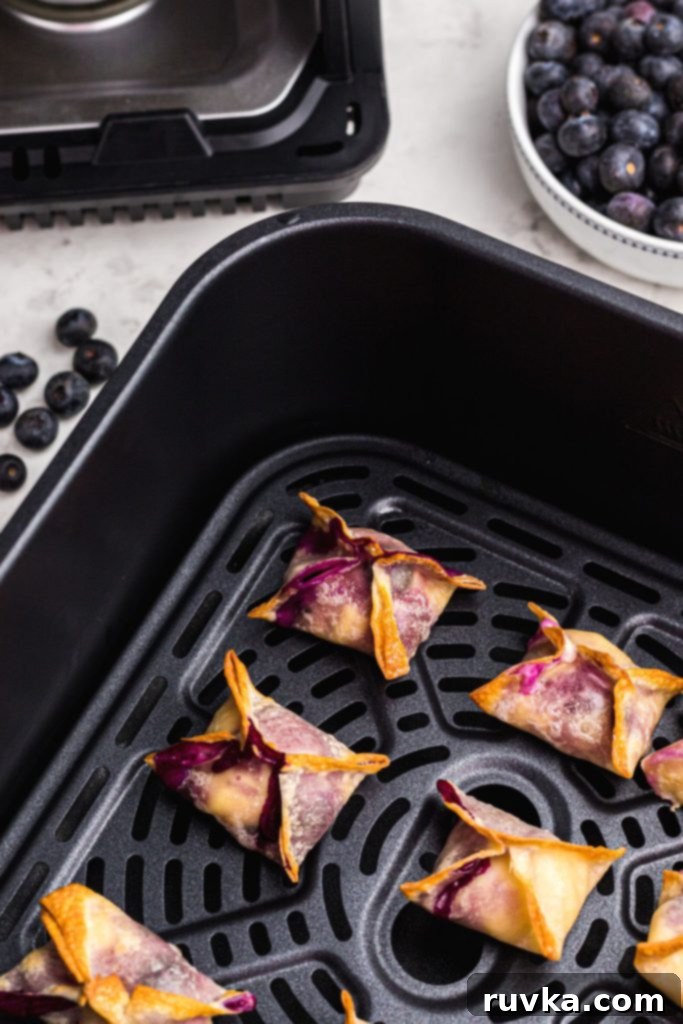 Crispy Air Fryer Blueberry Cheesecake Wontons 9 Golden crispy wontons filled with cream cheese cheesecake in the air fryer basket.