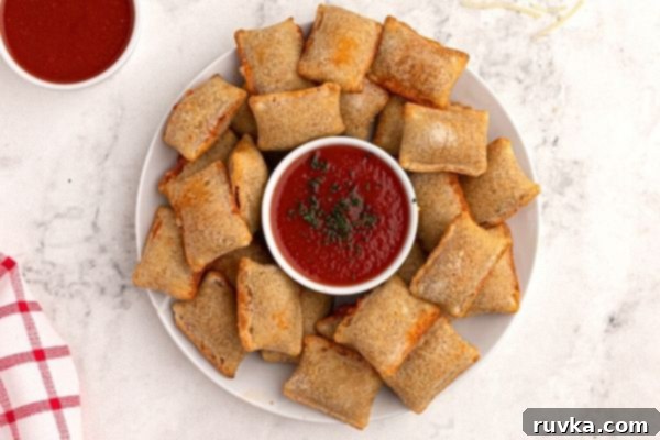 Golden Air Fryer Pizza Bites 2 Cooked and crispy, pizza rolls, served on a white plate with a red dipping sauce.