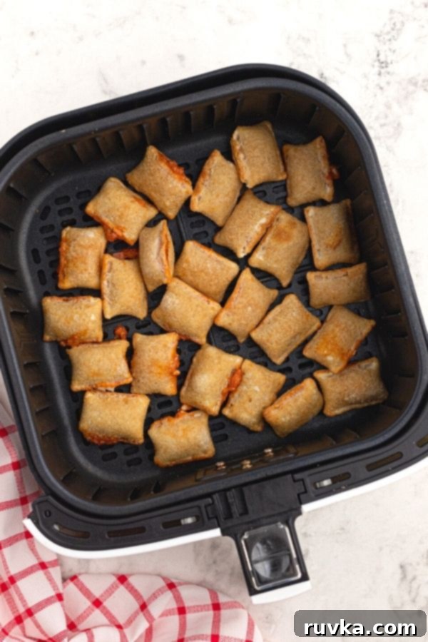 Golden Air Fryer Pizza Bites 4 Cooked pizza rolls in the the air fryer basket.