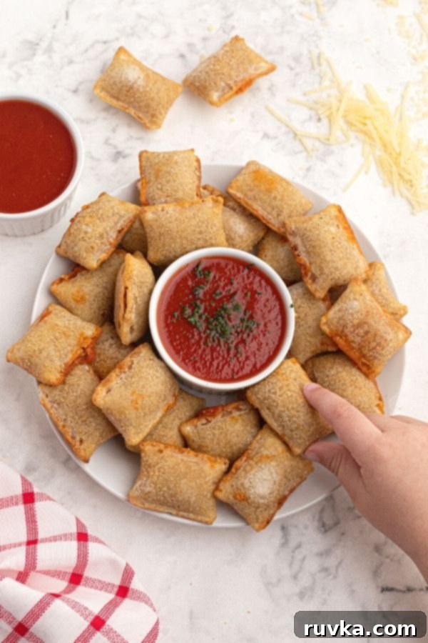 Golden Air Fryer Pizza Bites 5 Cooked rolls served on a white plate with red dipping sauce and grated cheese on the table.