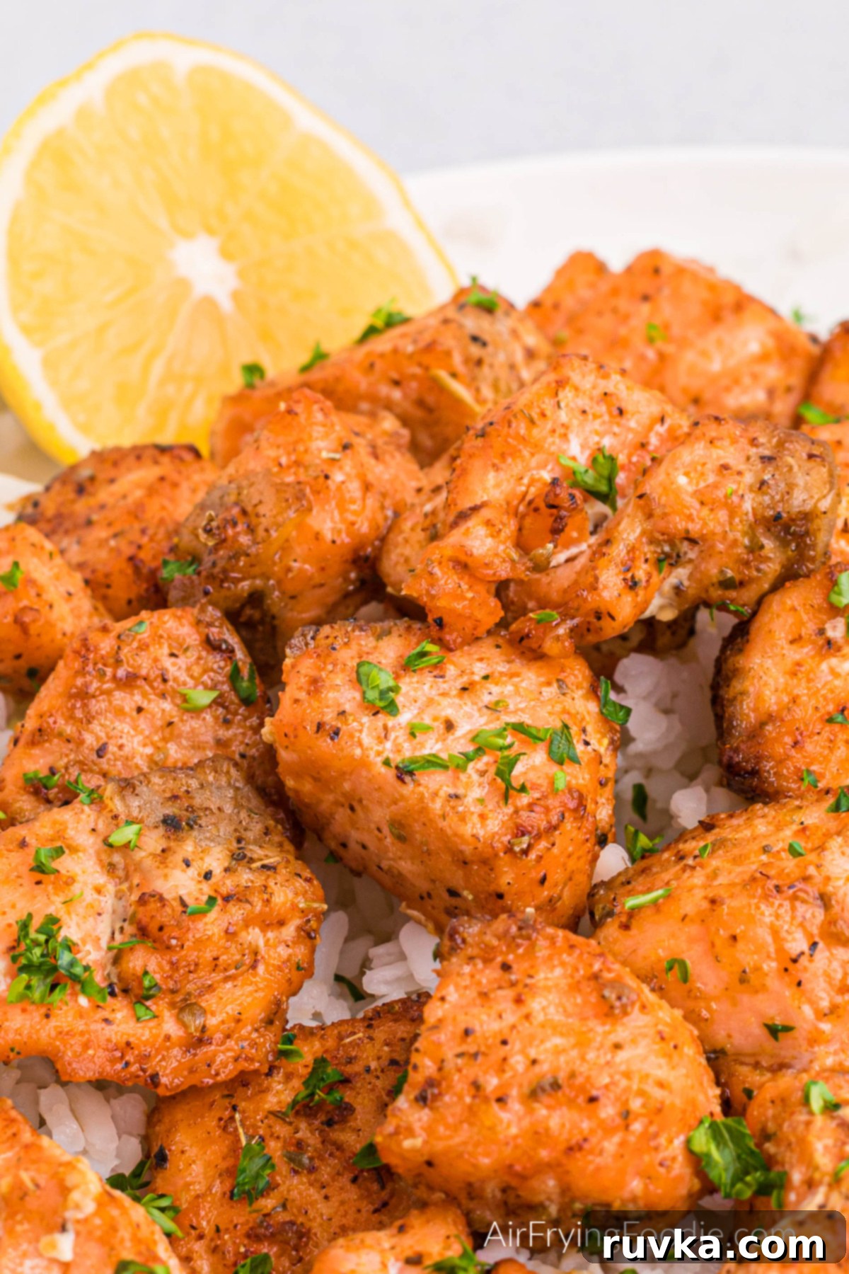 Spicy Air Fryer Blackened Salmon Bites 11 Close up of air fryer blackened salmon bites over a bed of rice served with a slice of lemon.