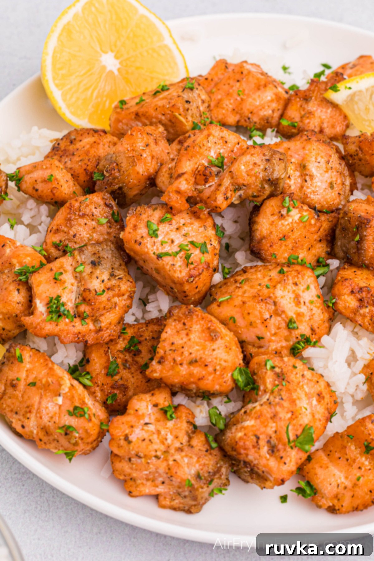 Spicy Air Fryer Blackened Salmon Bites 10 Blackened salmon bites made in the air fryer served over a bed of rice with a lemon wedge.