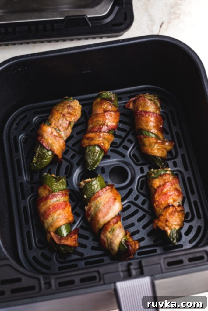 Perfect Air Fryer Texas Twinkies 9 Crispy golden bacon wrapped around stuffed jalapenos in an air fryer basket.