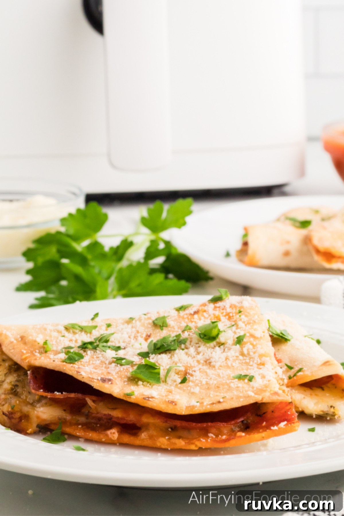 Crispy Air Fryer Pizza Quesadilla 9 A freshly made Air Fryer Pizza Quesadilla, garnished with parmesan cheese and fresh parsley, served on a white plate.