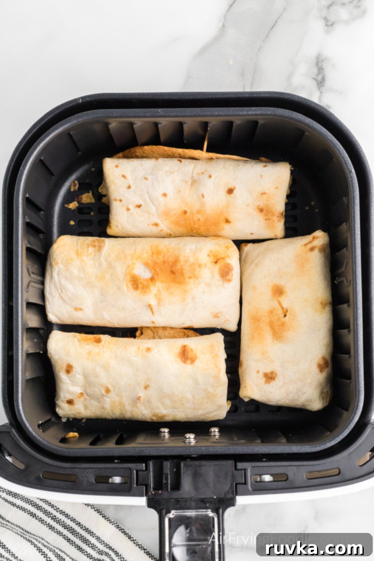 Crispy Air Fryer Chimichangas 8 Freshly air-fried chimichangas with a perfect golden-brown crisp, nestled in the basket of an air fryer, ready to be served.