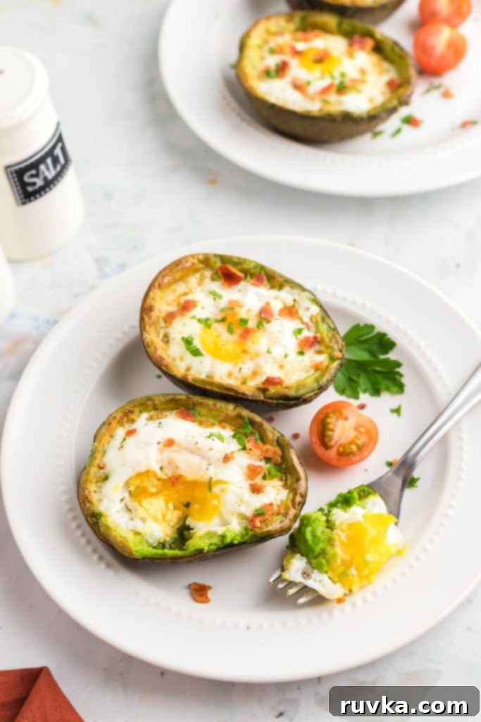 Air Fryer Avocado Egg Boats 7 Cooked eggs in avocado slices on a white plate with a fork bite out