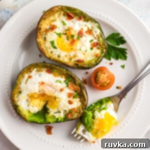 Air Fryer Avocado Egg Boats 8 Juicy avocados sliced open with egg cooked in center on a white plate.