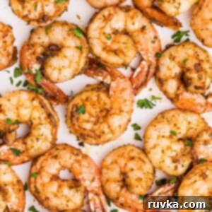 Crispy Air Fryer Shrimp 9 Juicy seasoned shrimp on a white plate garnished with parsley flakes