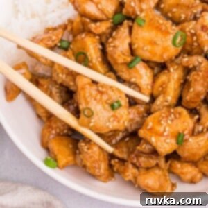 Crispy Air Fryer General Tso's Chicken 10 Golden juicy chicken pieces on a white plate being held by chopsticks