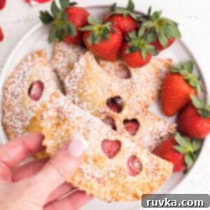 Easy Air Fryer Strawberry Nutella Hand Pies 10 A freshly baked strawberry Nutella hand pie, golden brown and glistening, held in a hand, emphasizing its deliciousness.