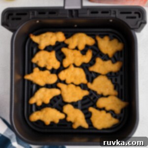 Crispy Air Fryer Dino Nuggets 8 Dino nuggets in air fryer basket, ready to serve.