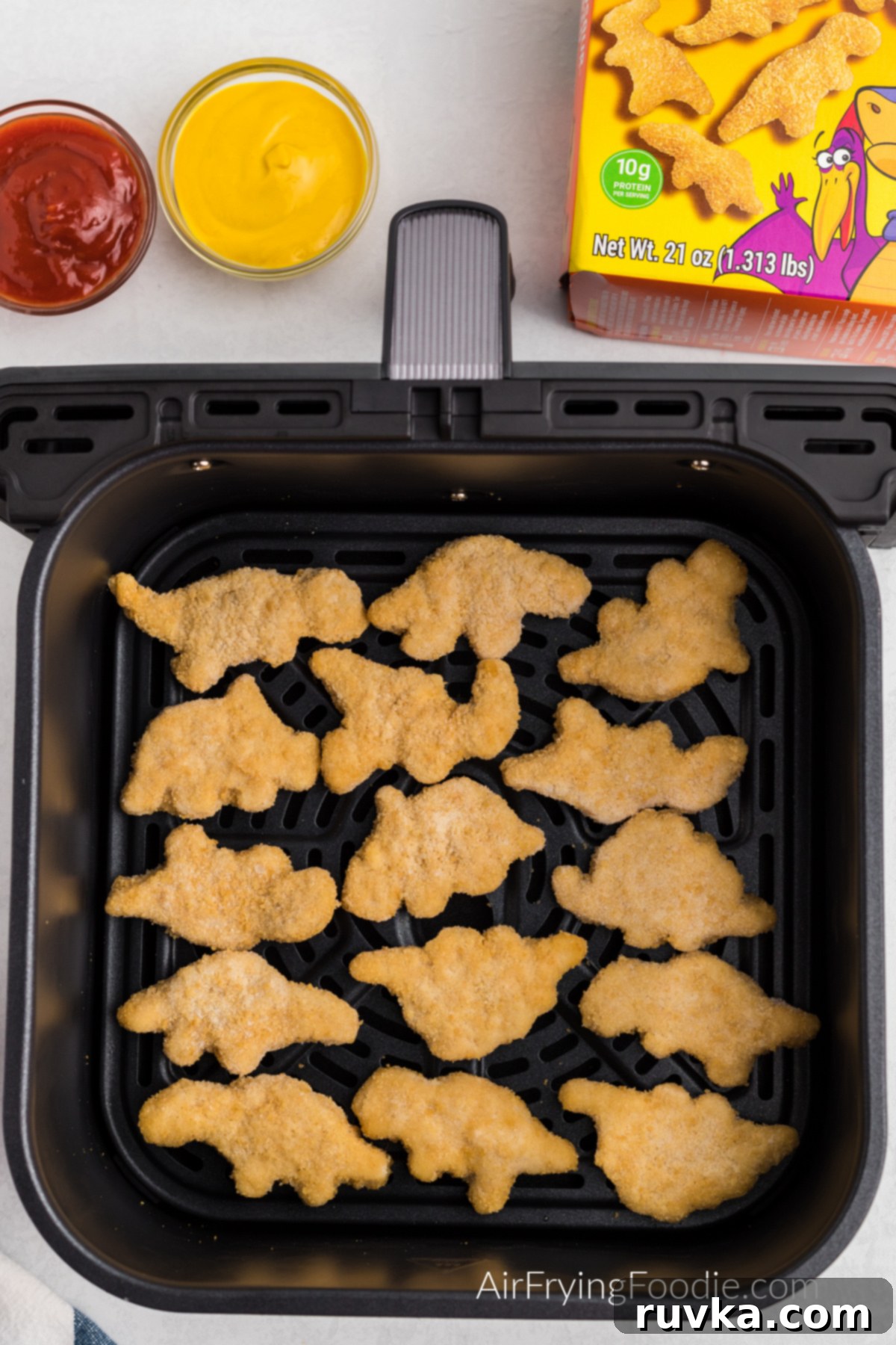 Crispy Air Fryer Dino Nuggets 4 Dino nuggets in the air fryer basket. Ready to cook.