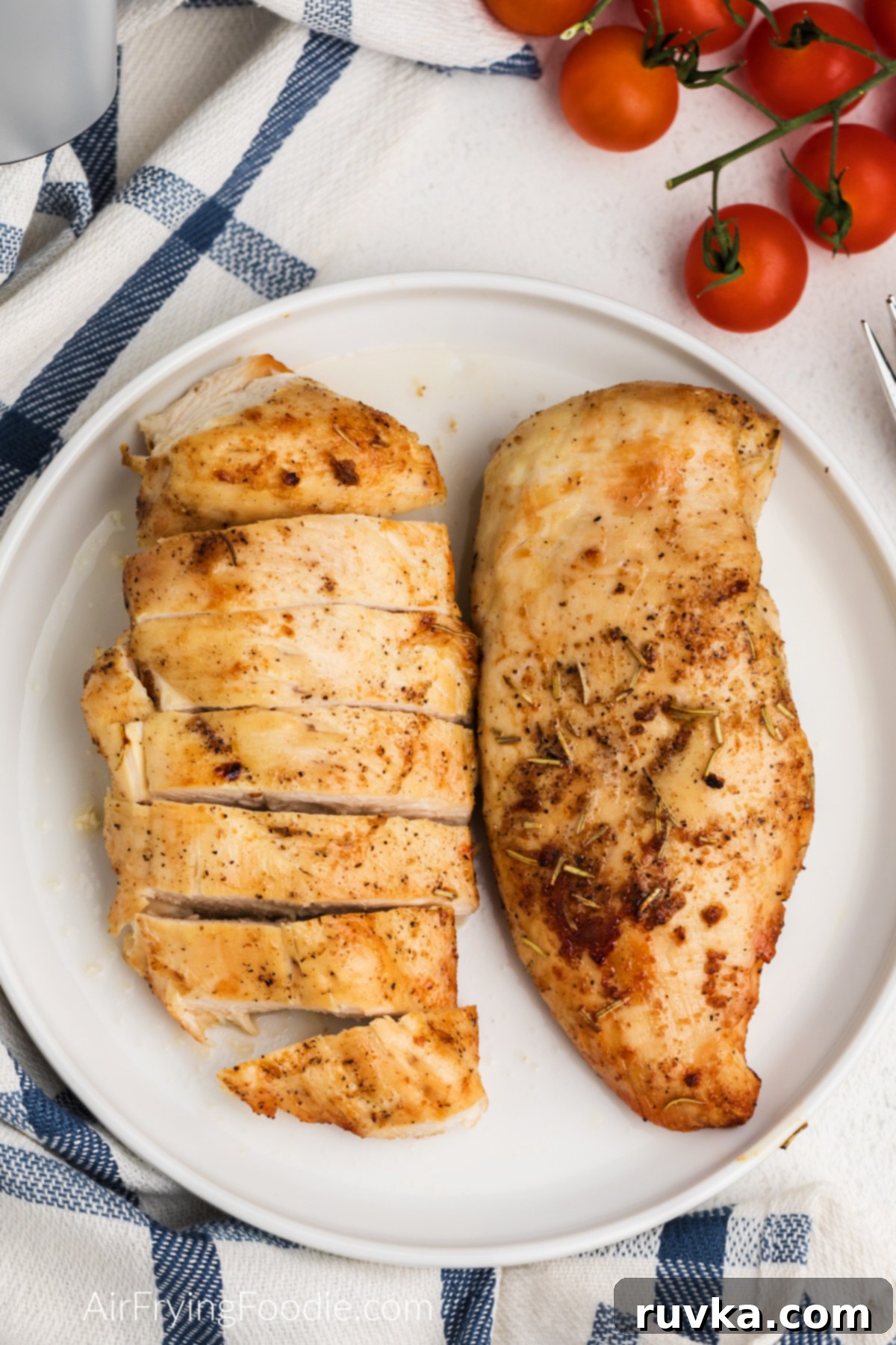 Juicy Air Fryer Grilled Chicken Breast 2 Seasoned, sliced, and whole grilled chicken breast made in the air fryer and served on a white plate.