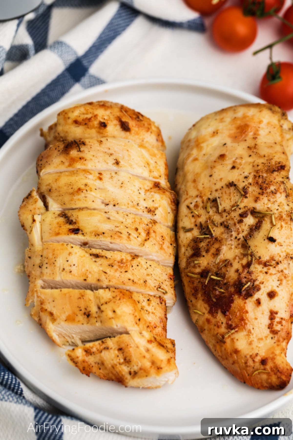 Juicy Air Fryer Grilled Chicken Breast 7 Air fryer grilled chicken breast on a white plate, sliced and whole chicken breasts on the plate.