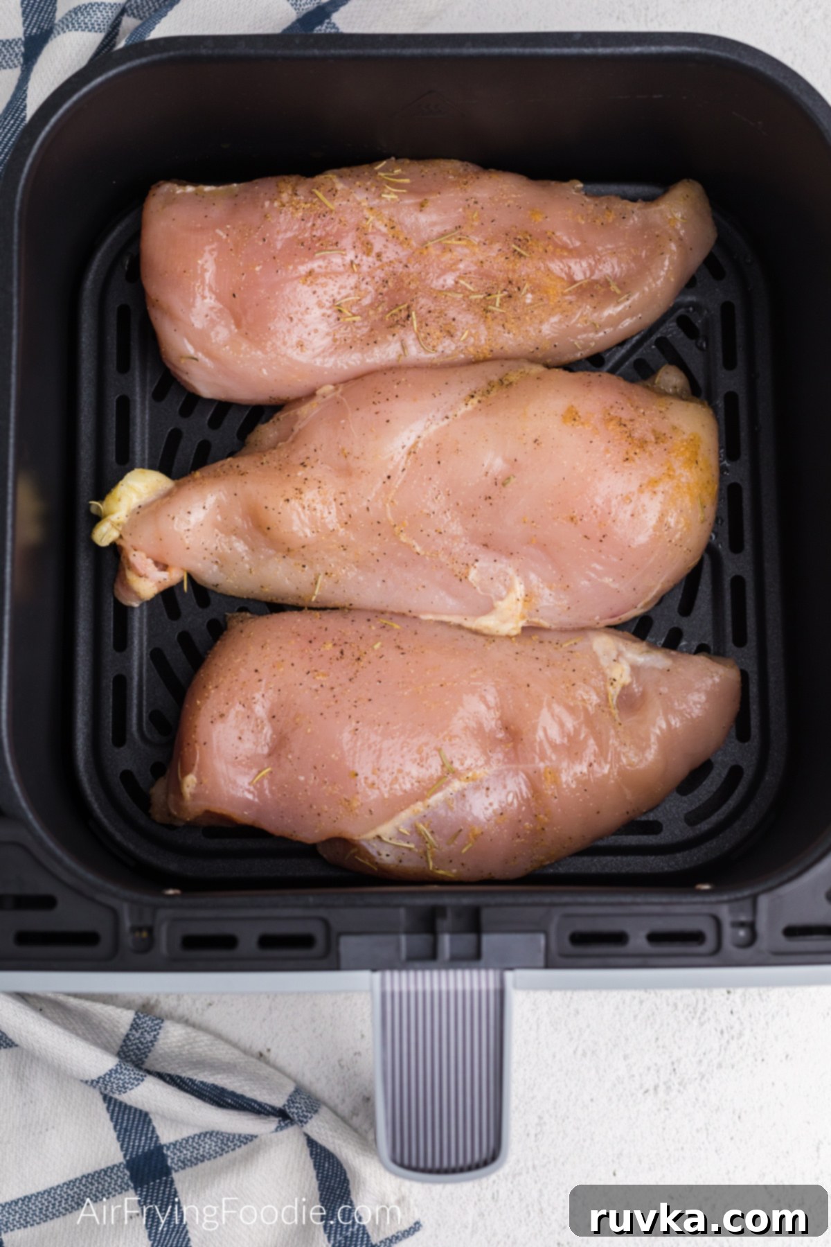 Juicy Air Fryer Grilled Chicken Breast 4 Seasoned chicken breast in a single layer on the air fryer basket.