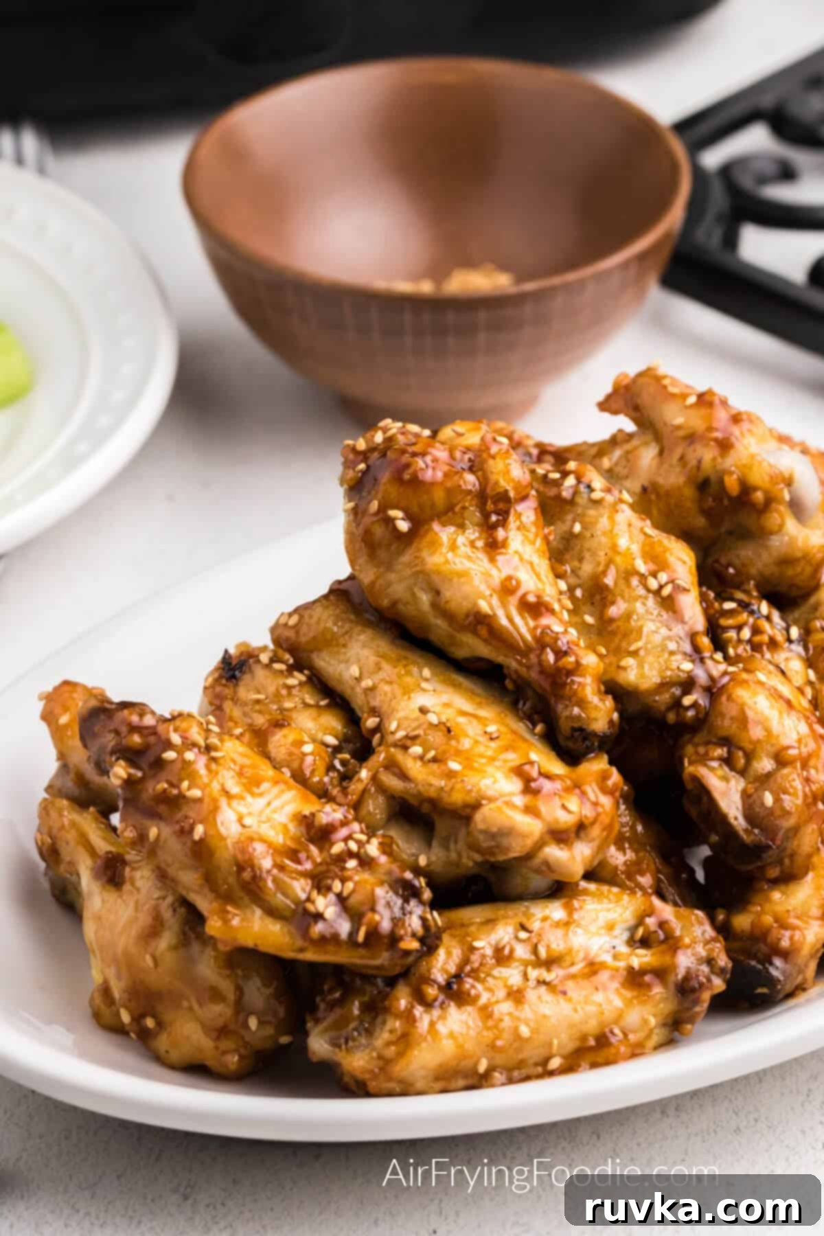 Crispy Honey Garlic Air Fryer Wings 2 honey garlic chicken wings made in the air fryer and served up on a white plate.