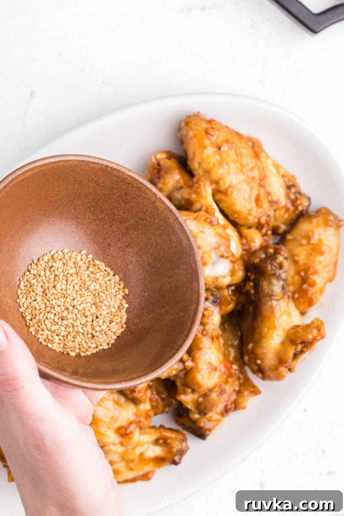Crispy Honey Garlic Air Fryer Wings 9 Sesame seeds about to be sprinkled over the honey garlic chicken wings.