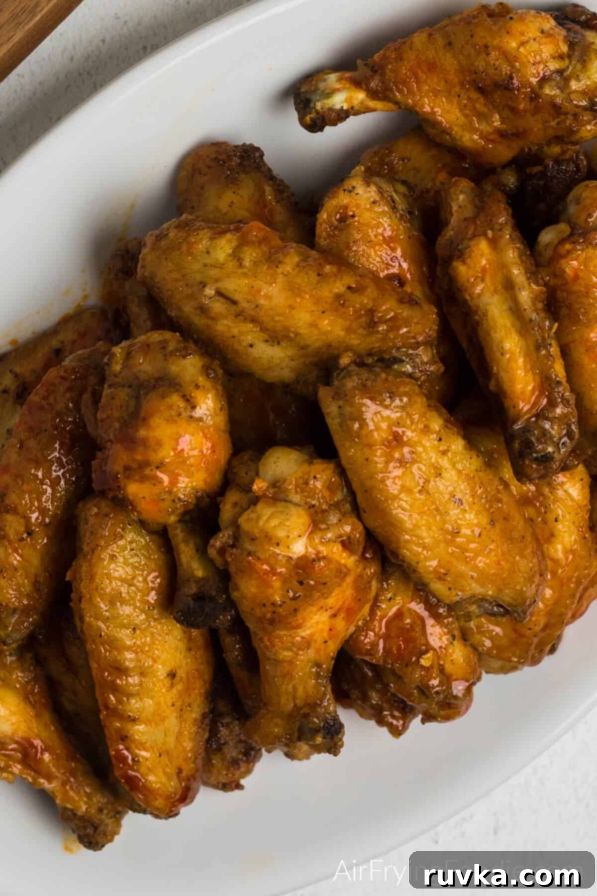 Crispy Air Fryer Buffalo Wings 11 air fryer buffalo chicken wings tossed in sauce and served on a white platter.