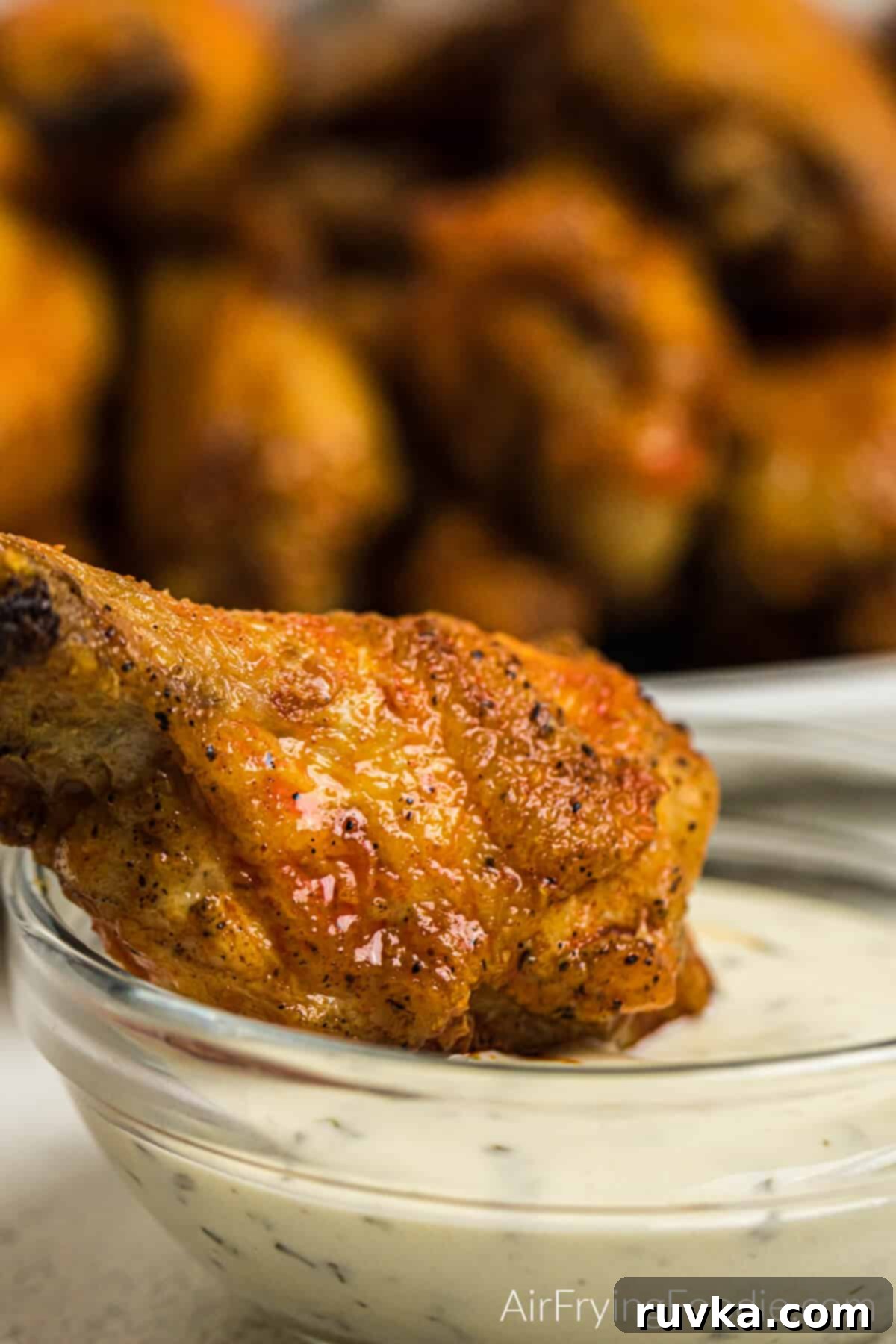 Crispy Air Fryer Buffalo Wings 12 Close up photo of air fryer buffalo chicken wing being dipped into a bowl of Ranch dressing.