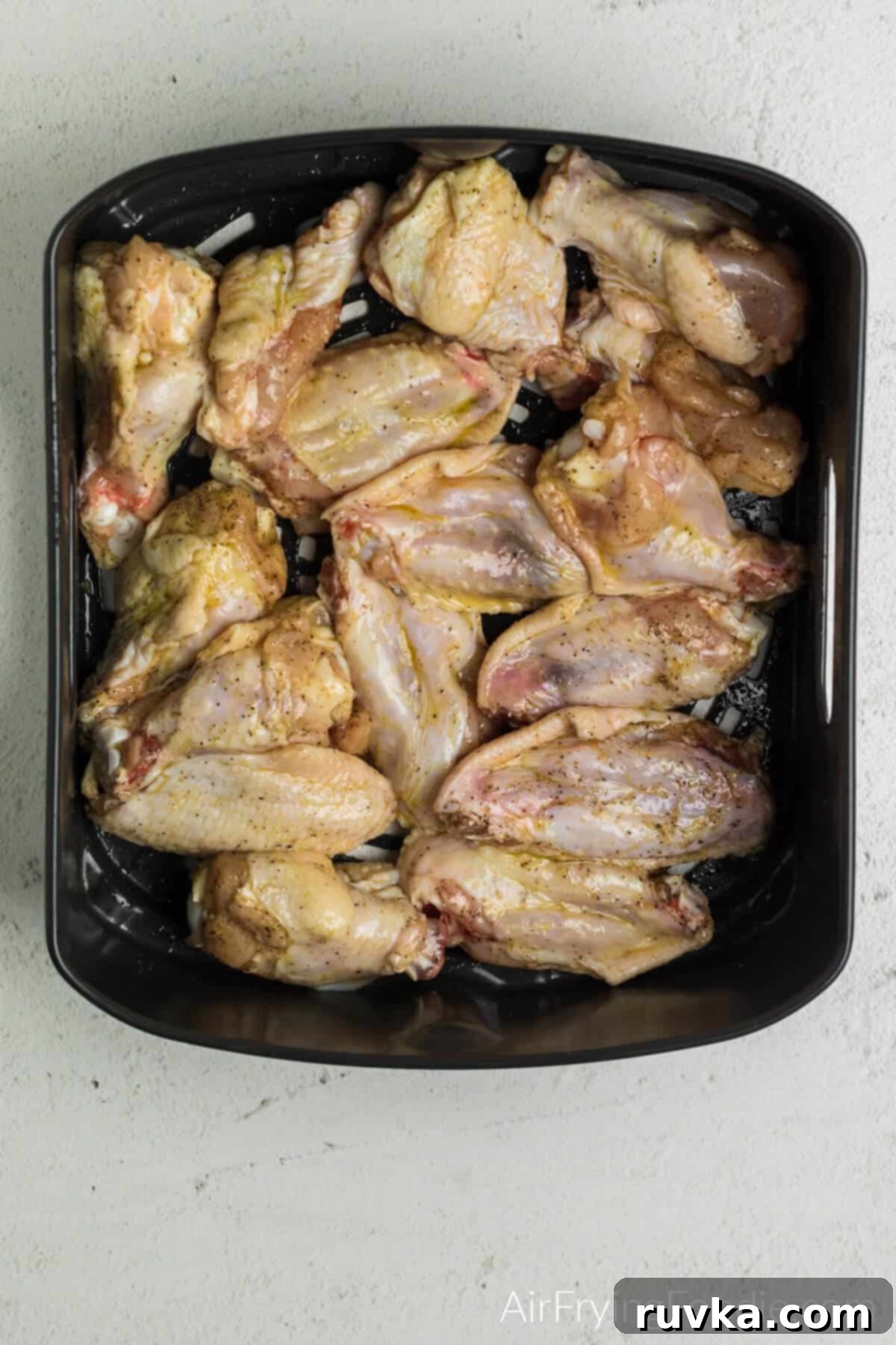 Crispy Air Fryer Buffalo Wings 7 Seasoned wings placed into the air fryer basket.