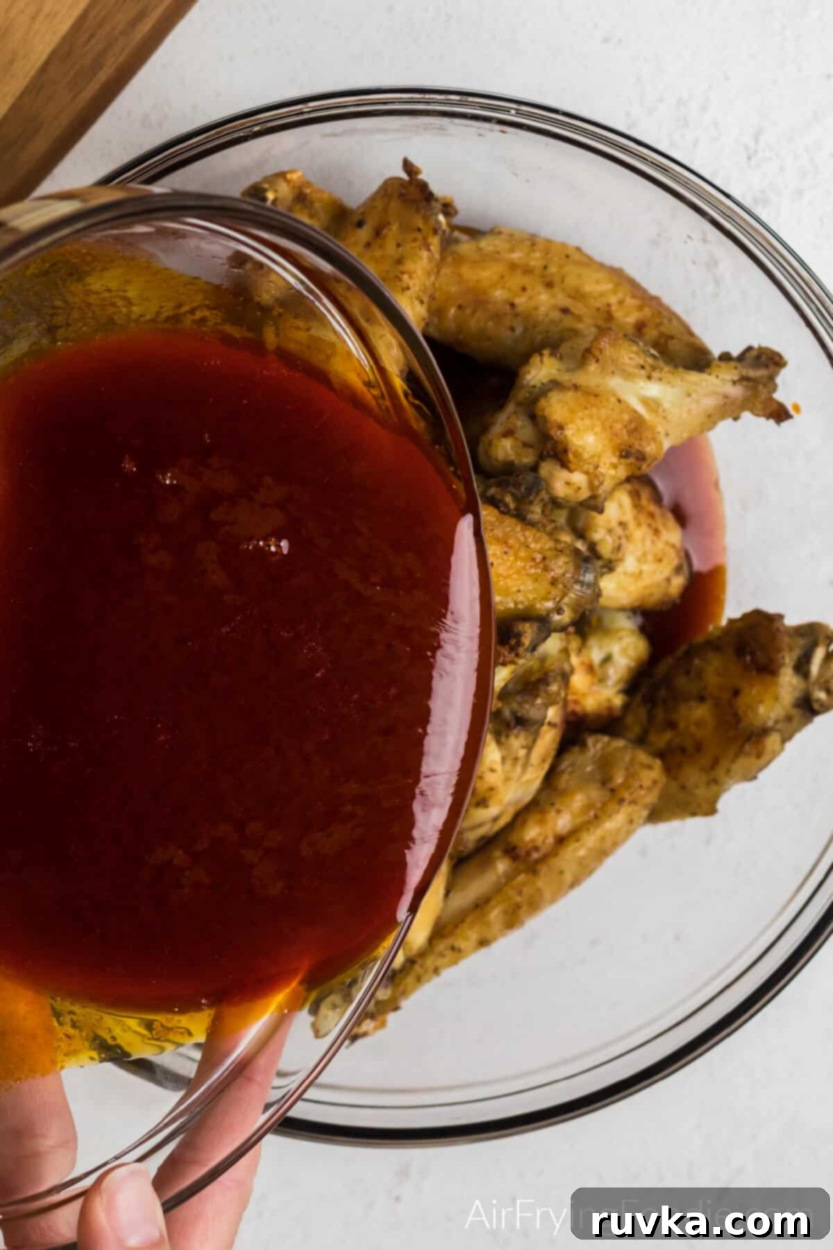 Crispy Air Fryer Buffalo Wings 10 Pouring homemade wing sauce over the cooked wings.